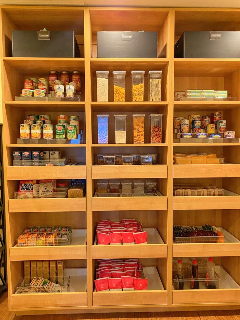 After: the family&rsquo;s walk-in pantry restocked with clear canisters, labeled bins and neatly grouped food on wood shelves