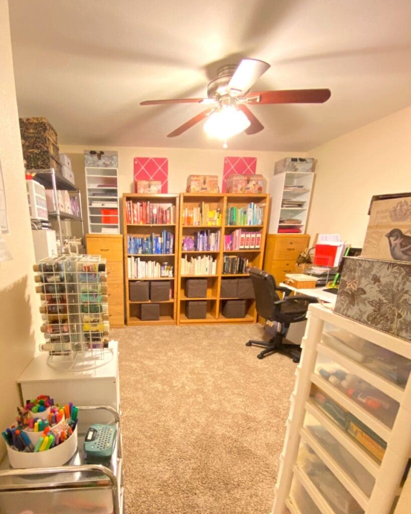 Same craft room and home office after organizing, with a clear floor, labeled bookcase bins and supply carts