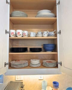 Kitchen cabinet after unpacking, with plates, bowls and mugs stacked neatly by size, San Diego