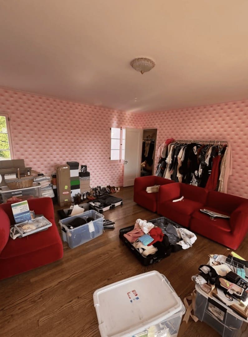 Cluttered dressing room with pink tufted walls, red velvet furniture, open suitcases and shoes before Simply Luxe organization for Vogue