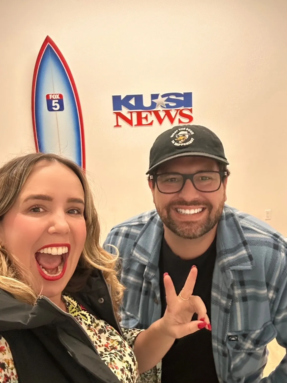 Smiling people posing at a news station.