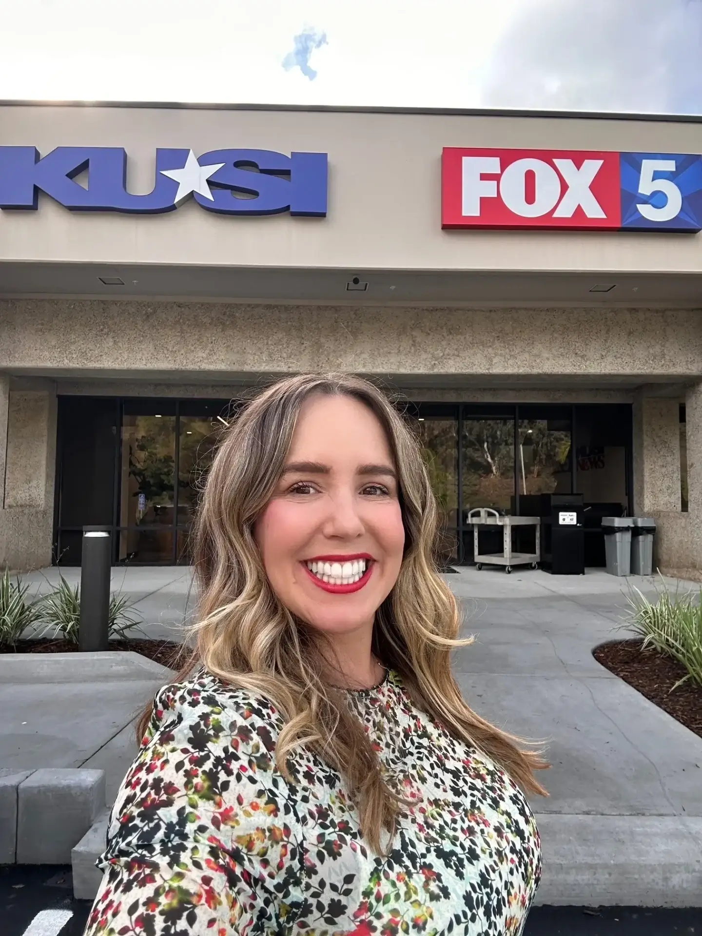 Smiling woman outside TV station buildings.