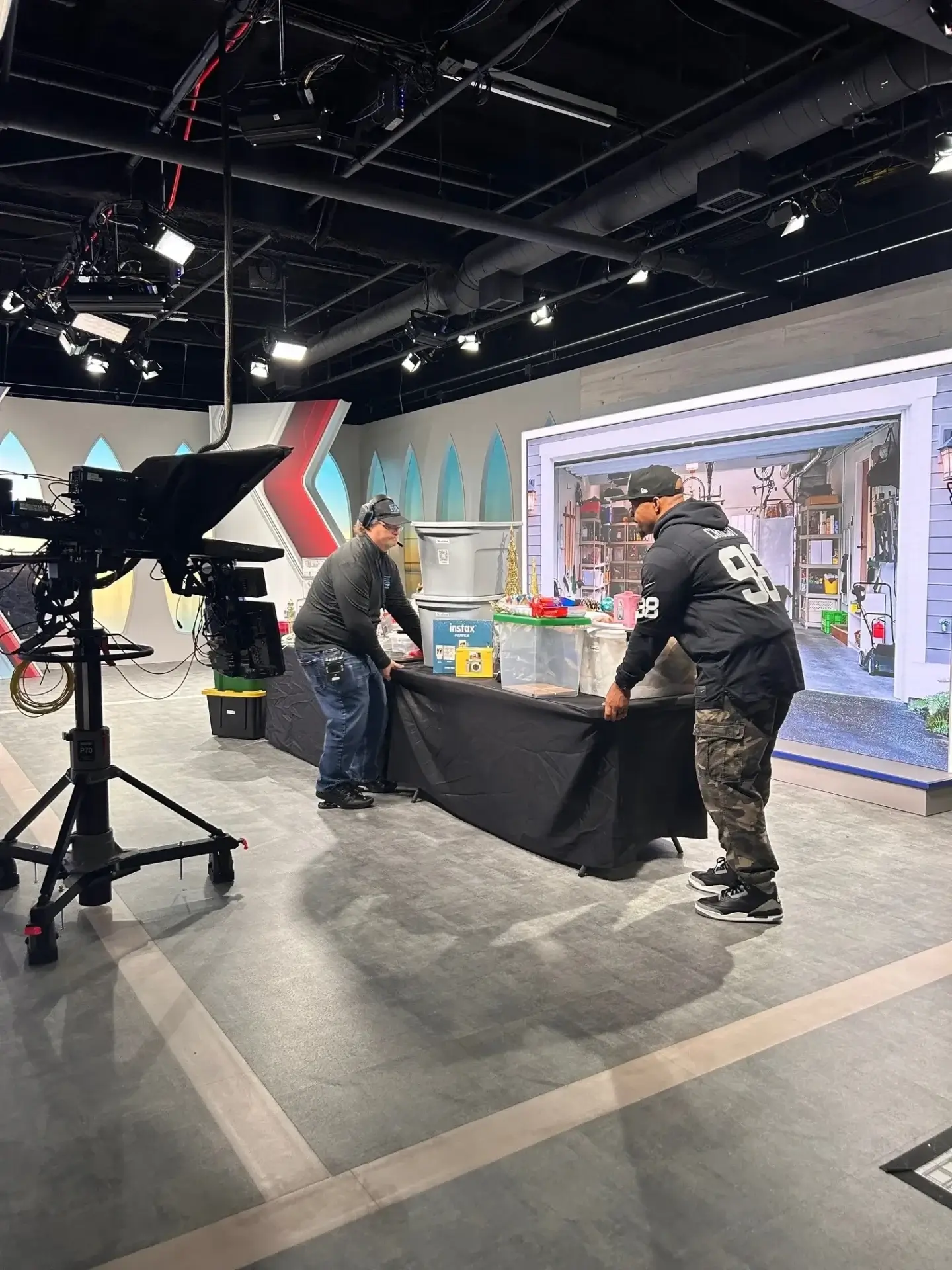 TV studio setup with two people arranging table.