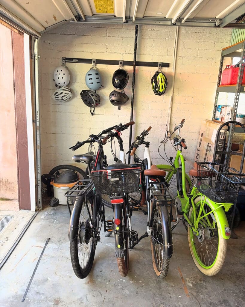 Garage bike storage after Simply Luxe organizing, with bikes lined up and helmets hung on a wall rail, North County San Diego