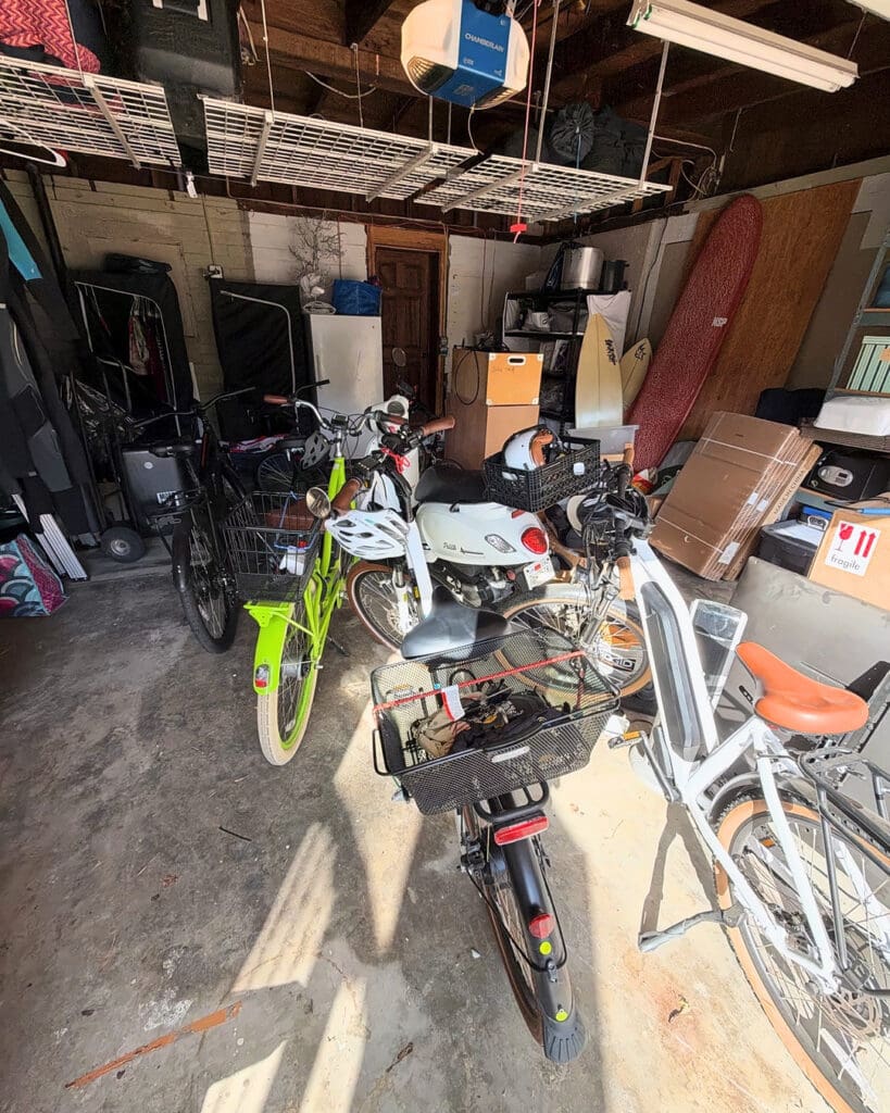 Garage before organizing, with bikes and scooters crowded together among boxes and clutter, North County San Diego