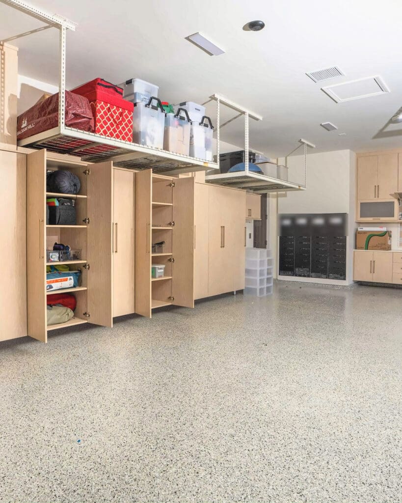 Same garage after Simply Luxe organizing, with the light wood cabinets filled, bins on the overhead racks and a clear epoxy floor, San Diego
