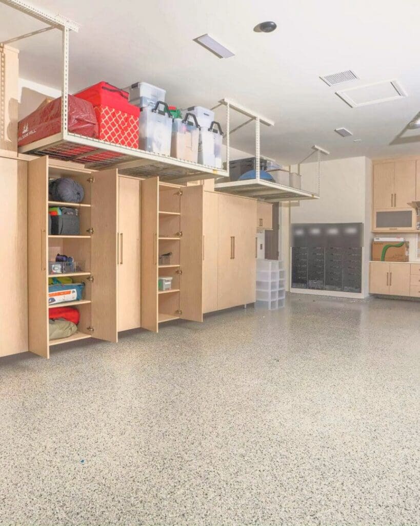 Same garage after Simply Luxe organizing, with the light wood cabinets filled, bins on the overhead racks and a clear epoxy floor, San Diego