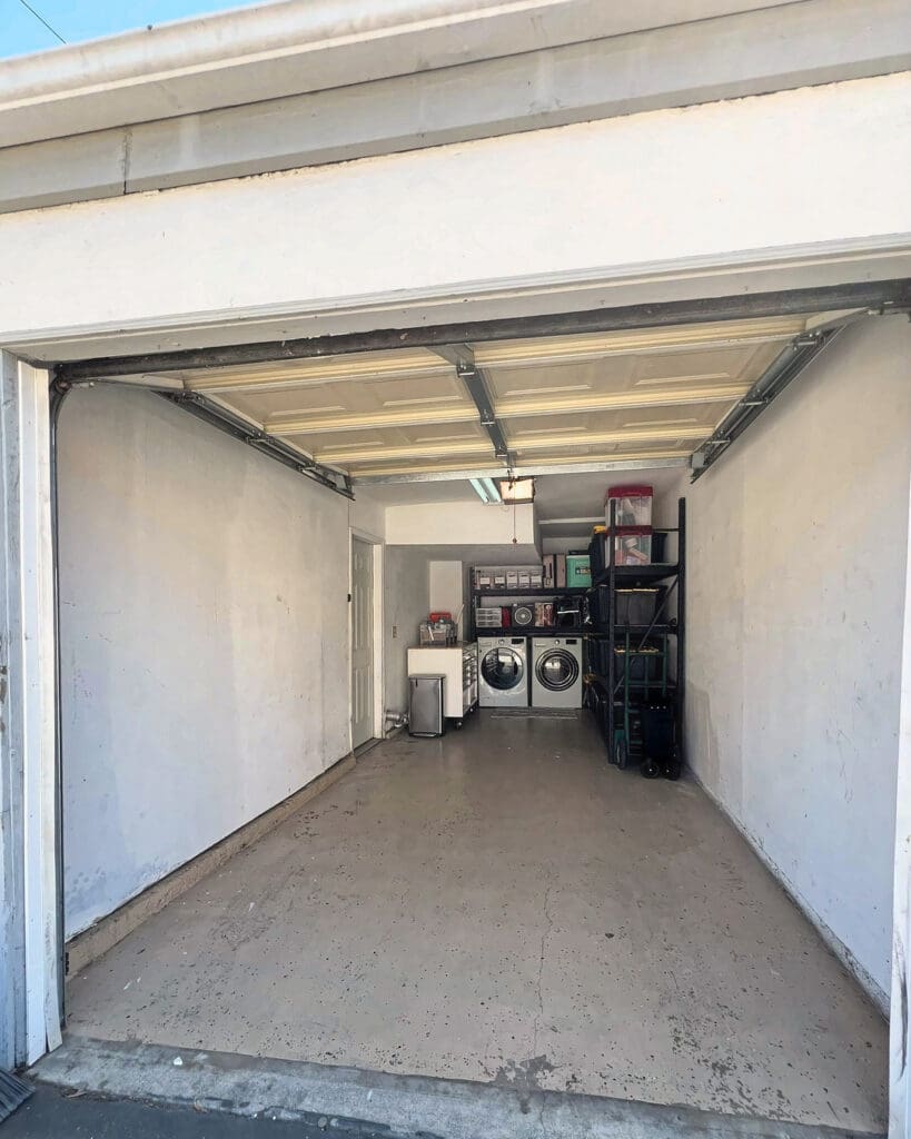 Same garage after Simply Luxe decluttering, cleared to an open floor with the washer, dryer and a single shelving unit at the back