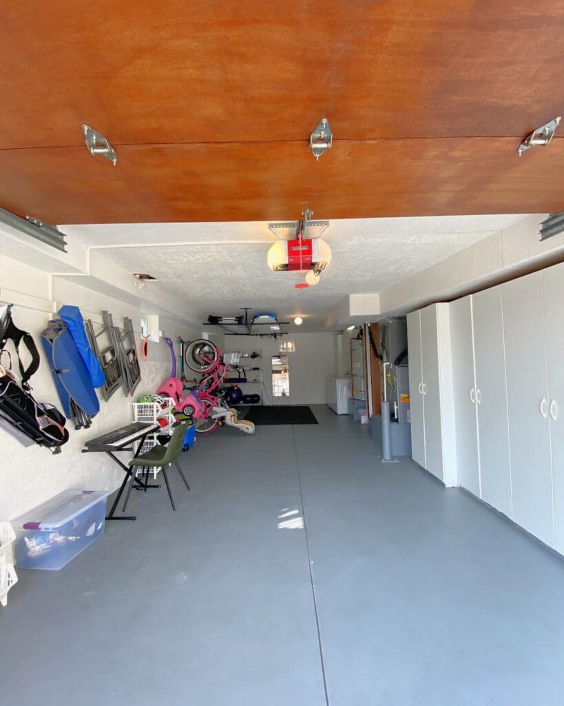 Same Mission Hills garage after, with bags, boards and bikes hung on the wall, bins under a bench and an open floor