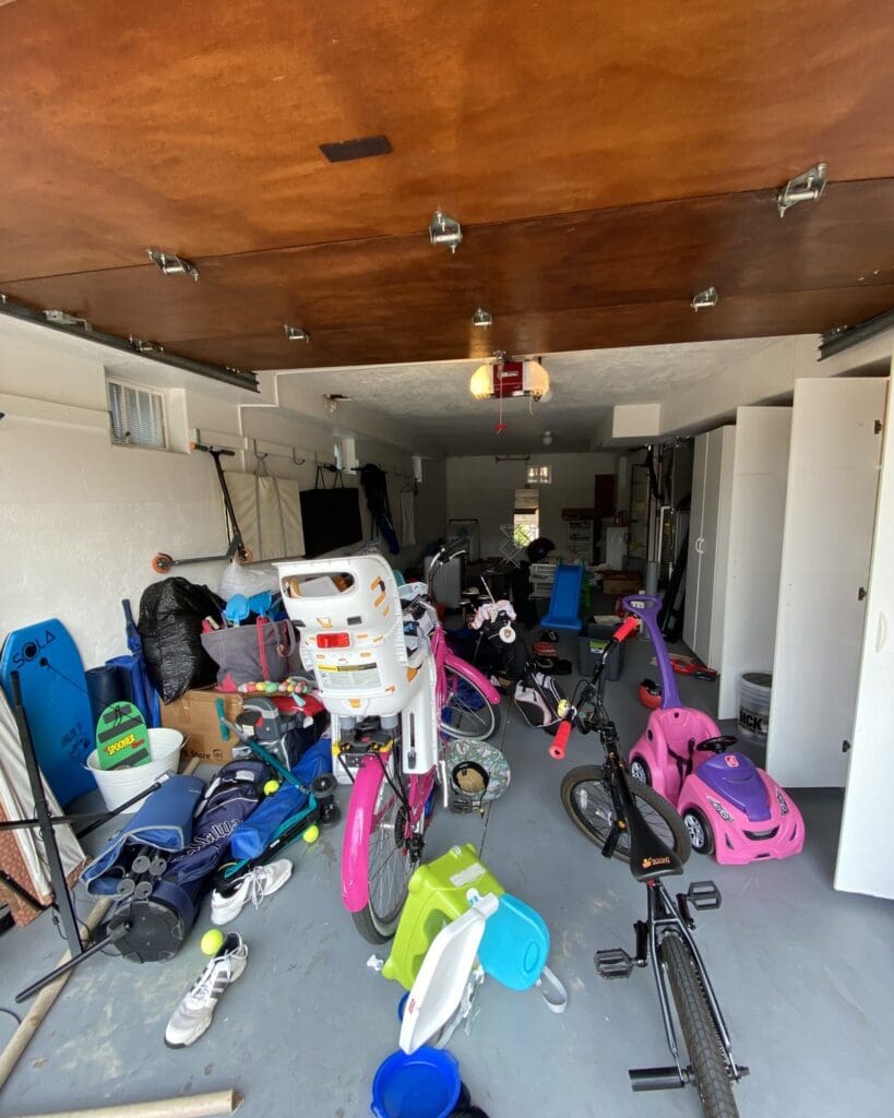 Garage before organizing in Mission Hills, with kids bikes, ride-on toys and sports gear covering the floor