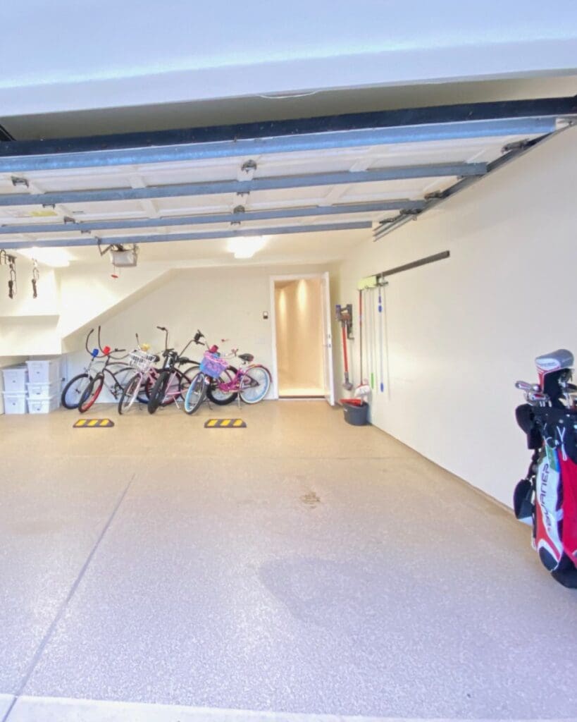 Same garage after organizing, with a clear floor, bikes lined up along the back wall and supplies in bins