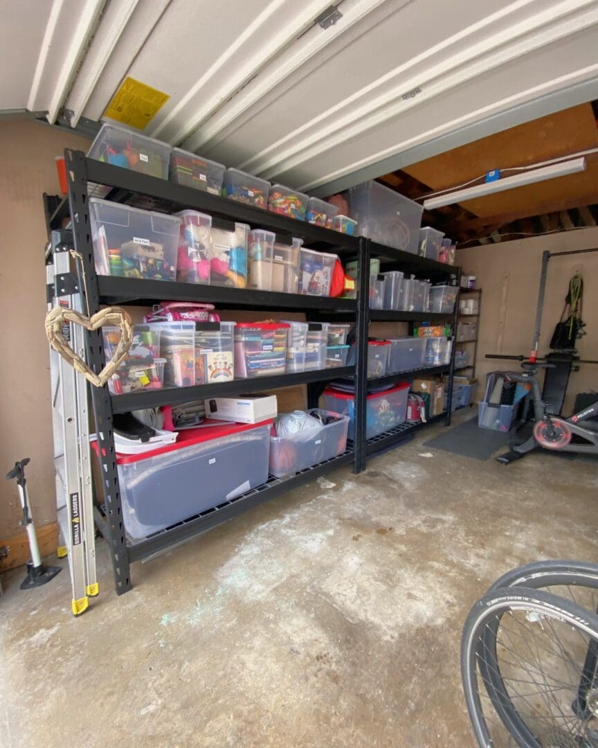 Same Woodland Hills garage after, seen from the open door, with labeled clear bins lined up on black metal shelving and the floor cleared