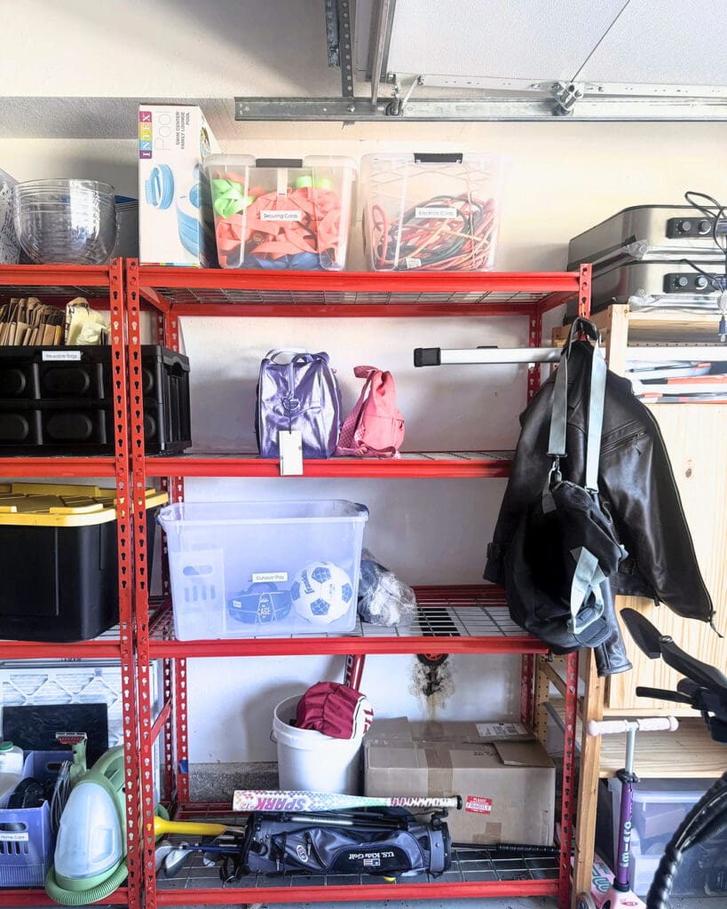 Same red garage shelving after Simply Luxe organizing, with clear and black bins sorted shelf by shelf, Anaheim
