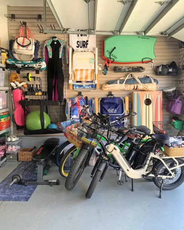 Same garage after a Simply Luxe slat wall install, with beach chairs, boards, bags and a wetsuit hung up and the bikes parked in a row, Huntington Beach
