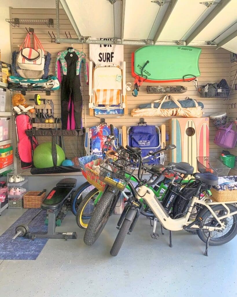 Same garage after a Simply Luxe slat wall install, with beach chairs, boards, bags and a wetsuit hung up and the bikes parked in a row, Huntington Beach