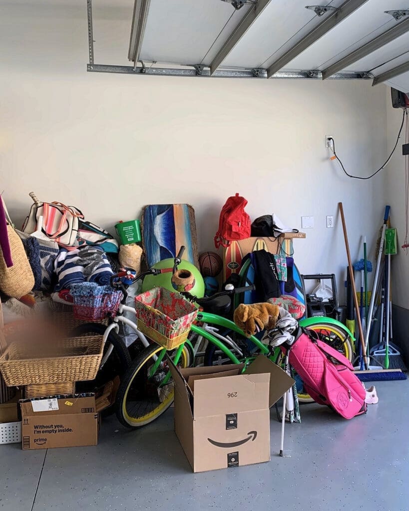 Garage before organizing, with bikes, boogie boards, beach bags and boxes piled against a bare wall, Huntington Beach home
