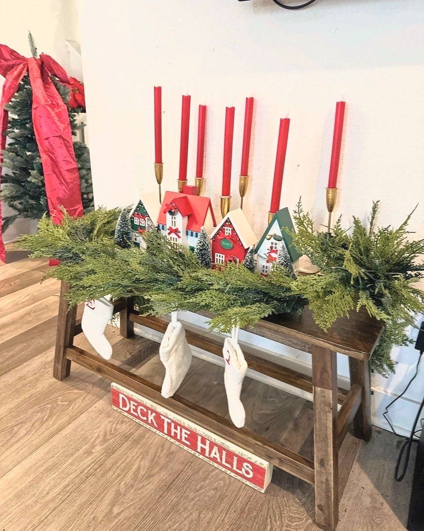 Entry console styled for the holidays by Simply Luxe with greenery garland, red taper candles, mini houses and stockings