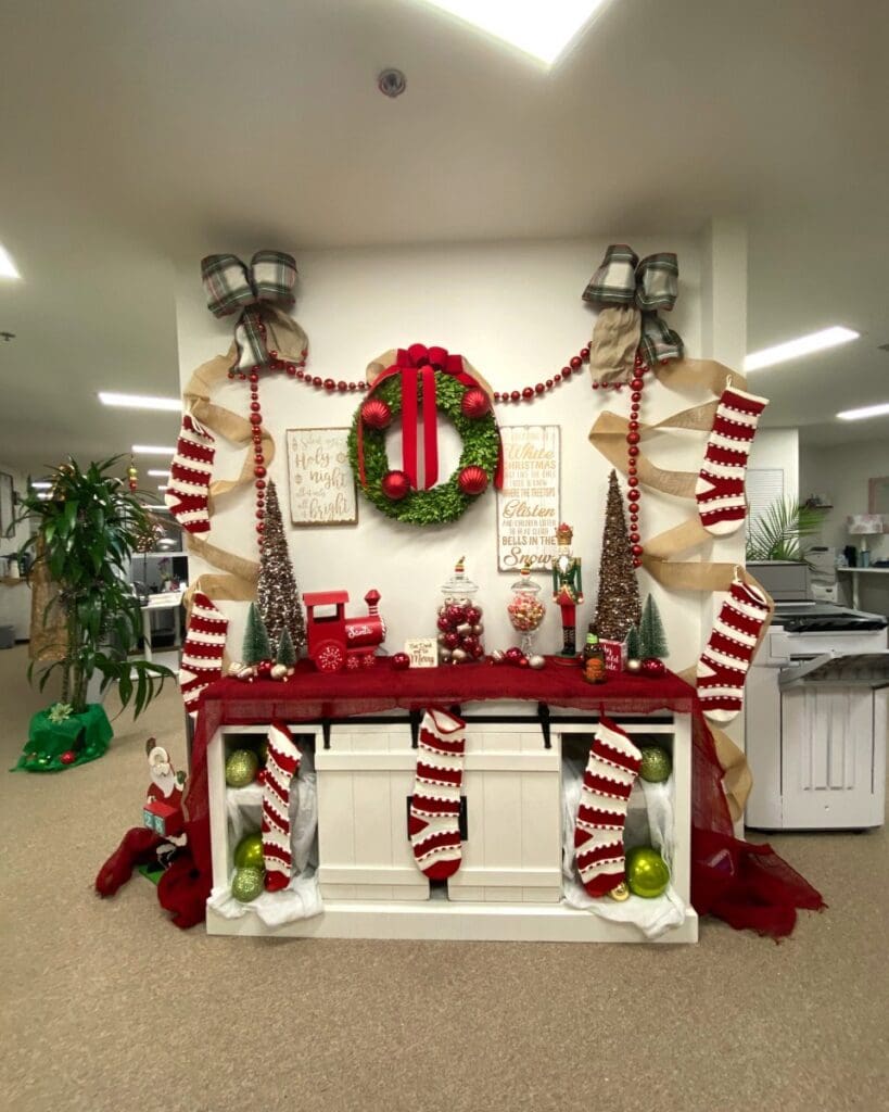 Same office console after holiday decorating, with a monogram wreath, garland, stockings and mini trees