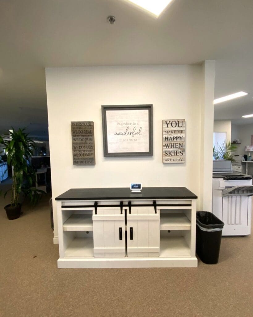 Office entry console before holiday decorating, with plain framed signs on a white wall