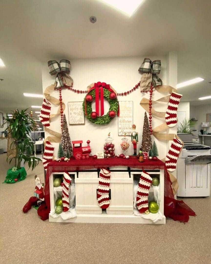 Same office console after Simply Luxe holiday decorating, with a wreath, garland, striped stockings, mini trees and plaid bows