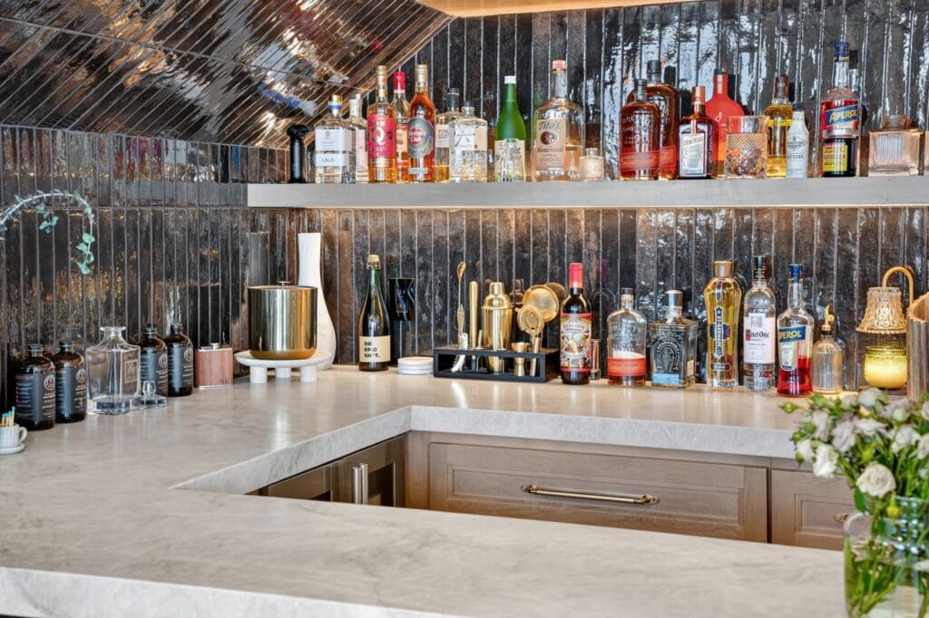 Organized home bar with open shelves and a dark tile backsplash after a remodel in Mission Viejo