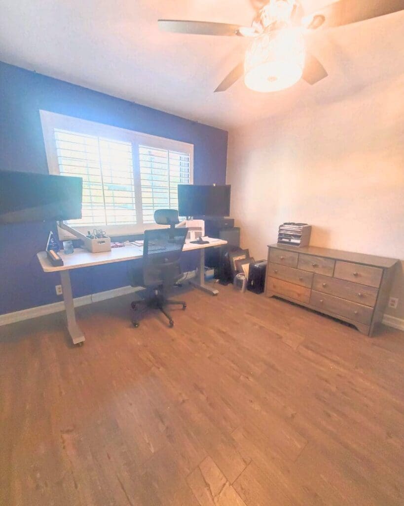 Home office after organizing, with two clear standing desks under the window and a tidy dresser for supplies