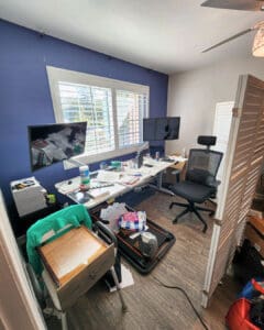 Home office before organizing: desks buried in paperwork, boxes and bins across the floor, Los Angeles