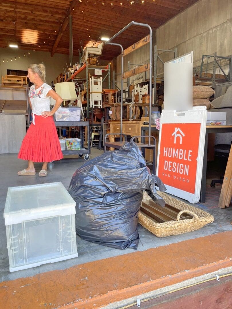 Inside the Humble Design San Diego warehouse, with the Humble Design sign, donation bags and a storage bin ready to be sorted