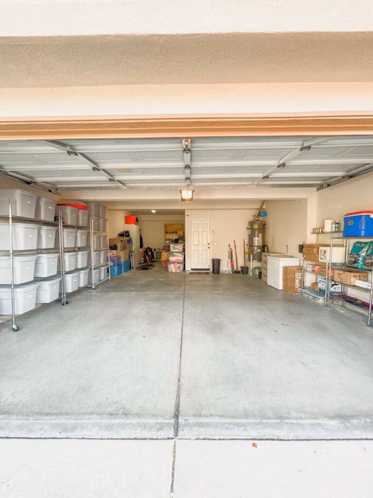 Two car garage with an open floor and plastic bin storage along the back wall