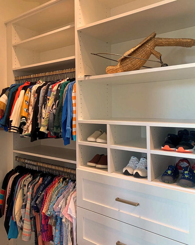 Kids closet midway through unpacking, with clothes hung and a few shoes and toys still finding a home, San Diego