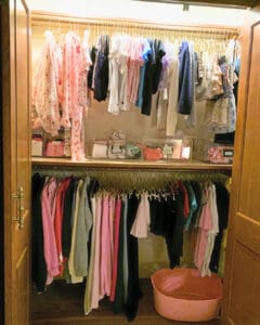 Kids closet after unpacking, with dresses and tops hung by color and a bin below, Newport Beach