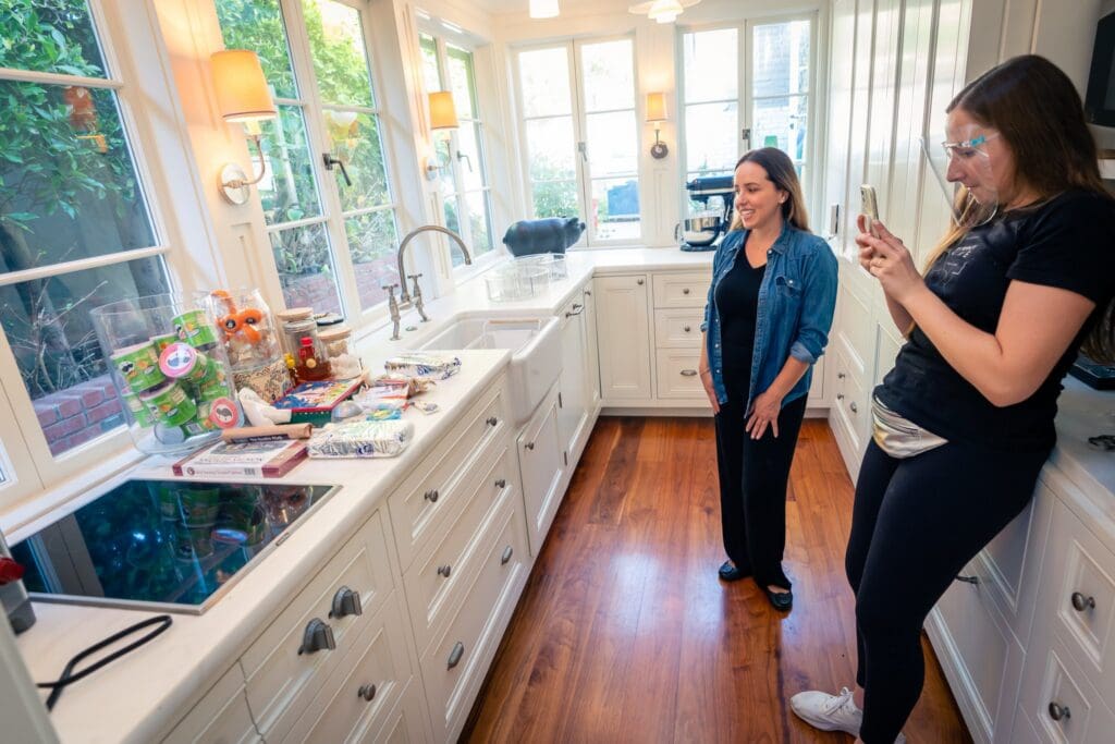 Simply Luxe organizer in a bright white kitchen with open shelves while a teammate checks the plan