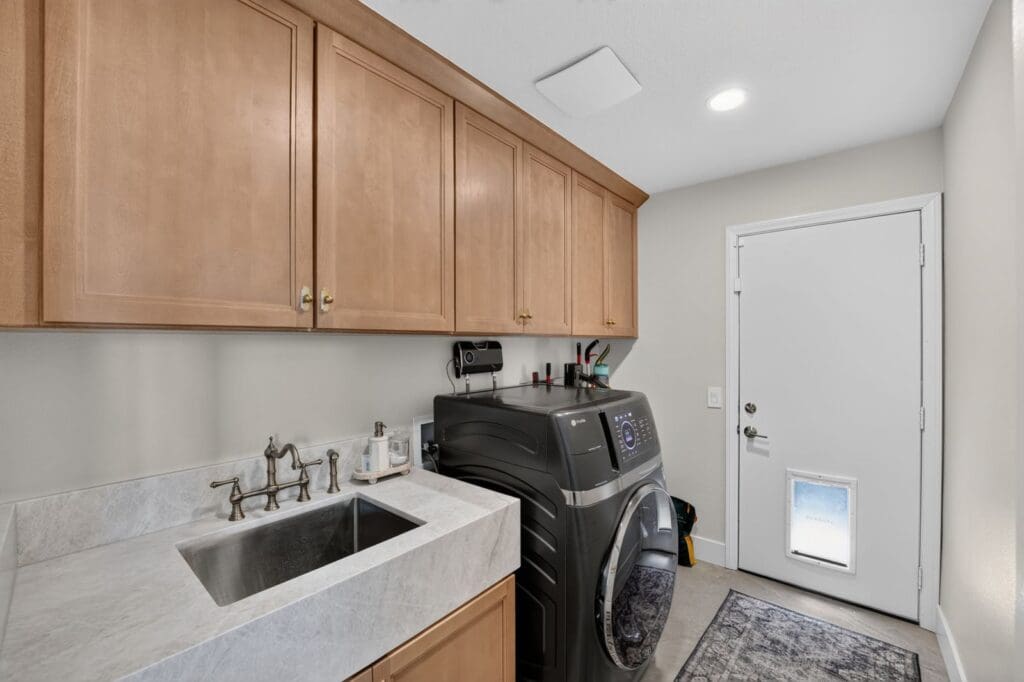 Bright laundry room with wood cabinets and a utility sink after a remodel in Mission Viejo