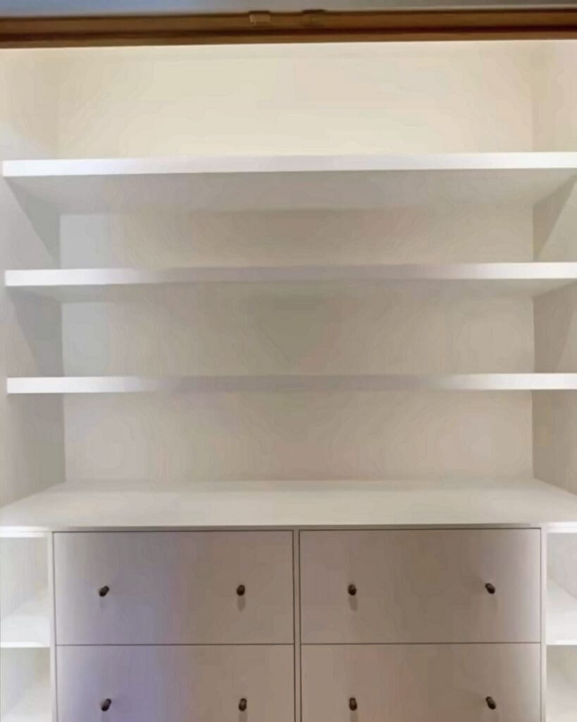 Empty white linen closet shelves above a row of drawers before organizing, Orange County home
