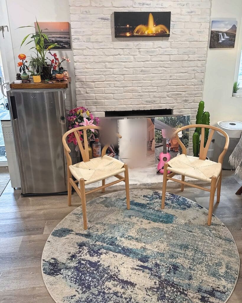 Same living room after Simply Luxe organizing, with a clear floor, two woven chairs and a round rug by the fireplace, Anaheim