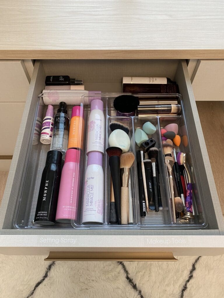 Makeup drawer with clear dividers holding lipsticks, brushes and palettes upright in a La Jolla dressing room