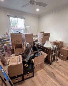 Room stacked with moving boxes, lamps and furniture on move in day before unpacking, San Diego