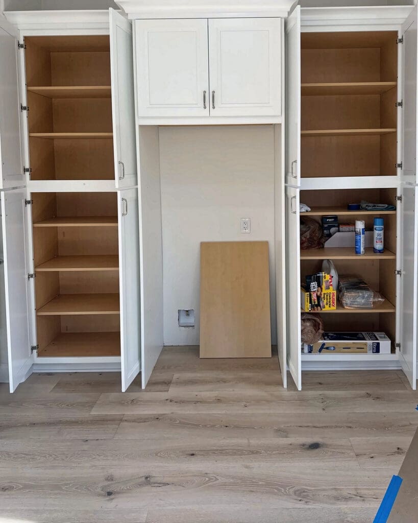 Kitchen built in cabinets before unpacking, shelves empty and a loose board leaning in the open fridge space, San Diego move