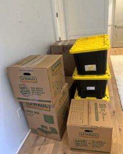 Moving boxes and yellow bins stacked against a wall on move in day, Del Mar