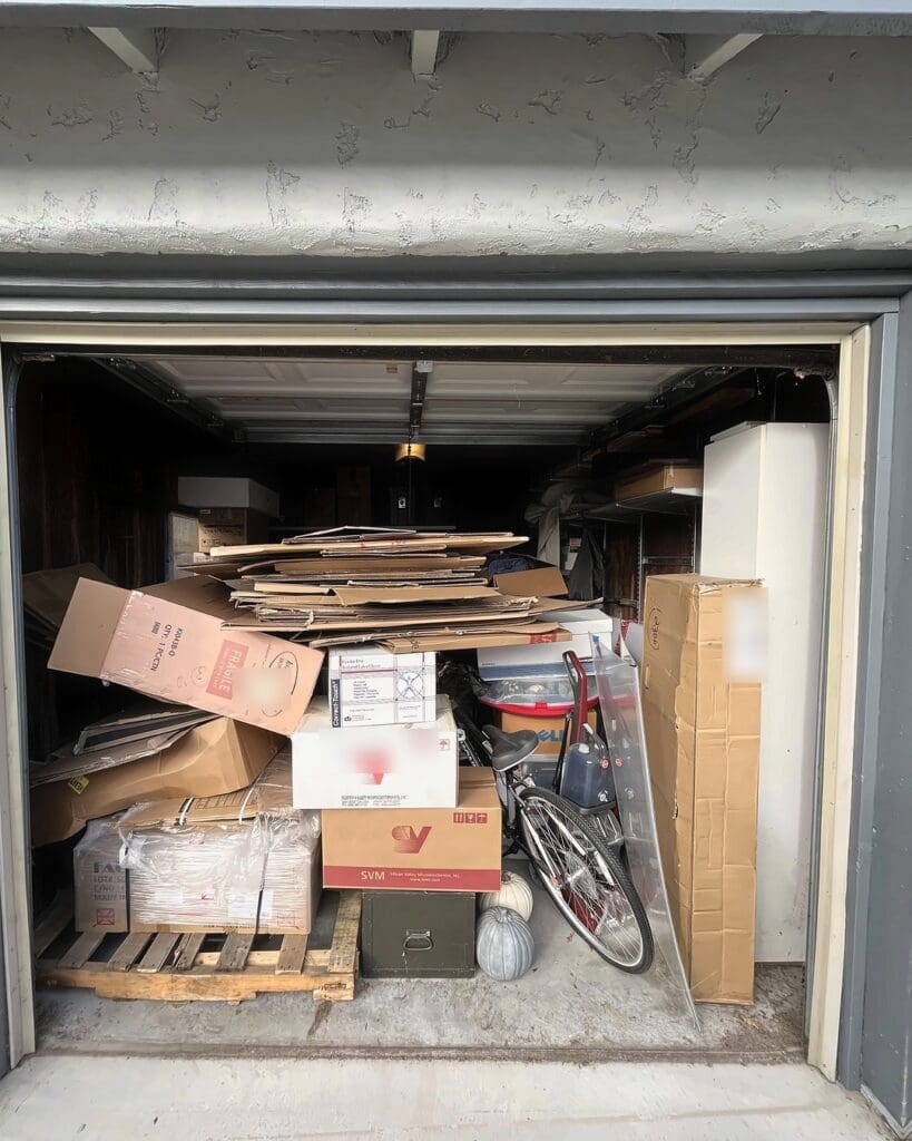 One car garage before organizing, packed nearly to the ceiling with moving boxes, flattened cardboard, a bike and a pallet, San Diego home
