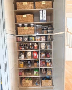 Pantry after unpacking, with woven baskets, clear jars and snacks sorted shelf by shelf, Del Mar