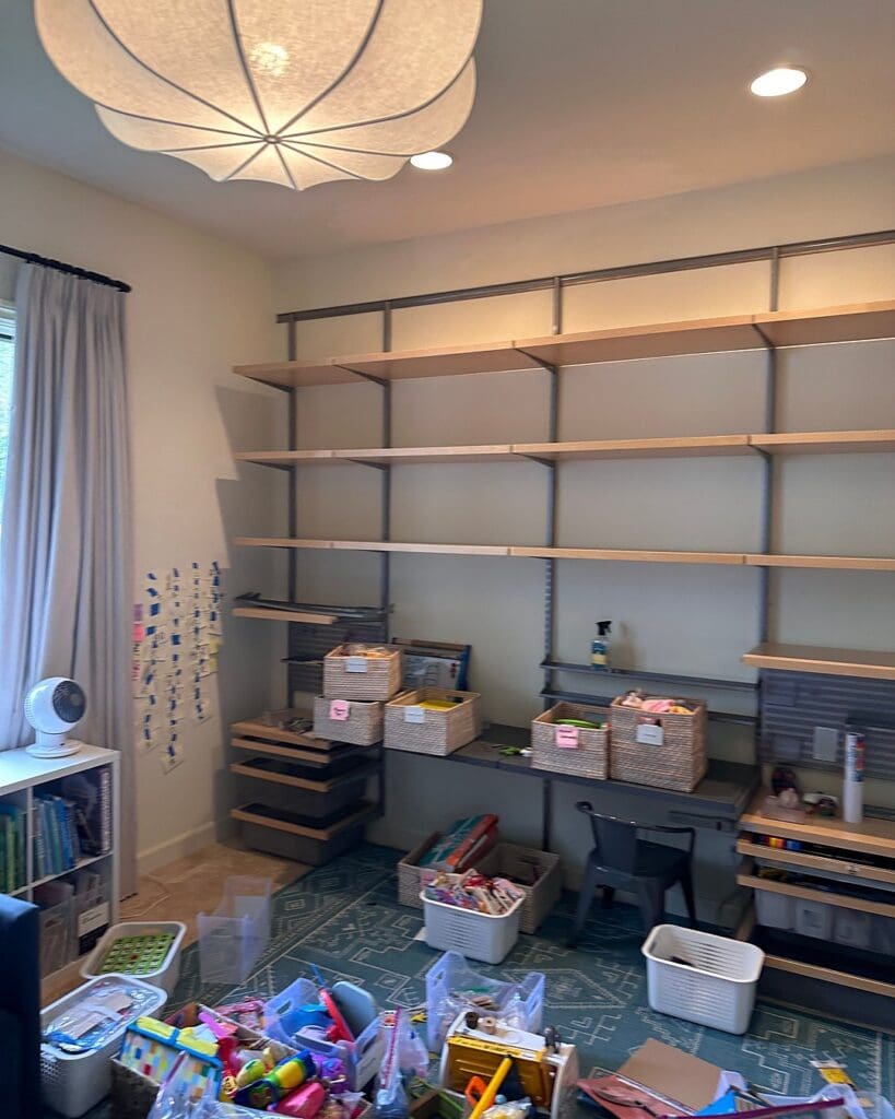 Kids playroom before baskets were placed on the wall shelves, with empty upper shelves, toys on the teal rug and a desk in progress, Solana Beach home