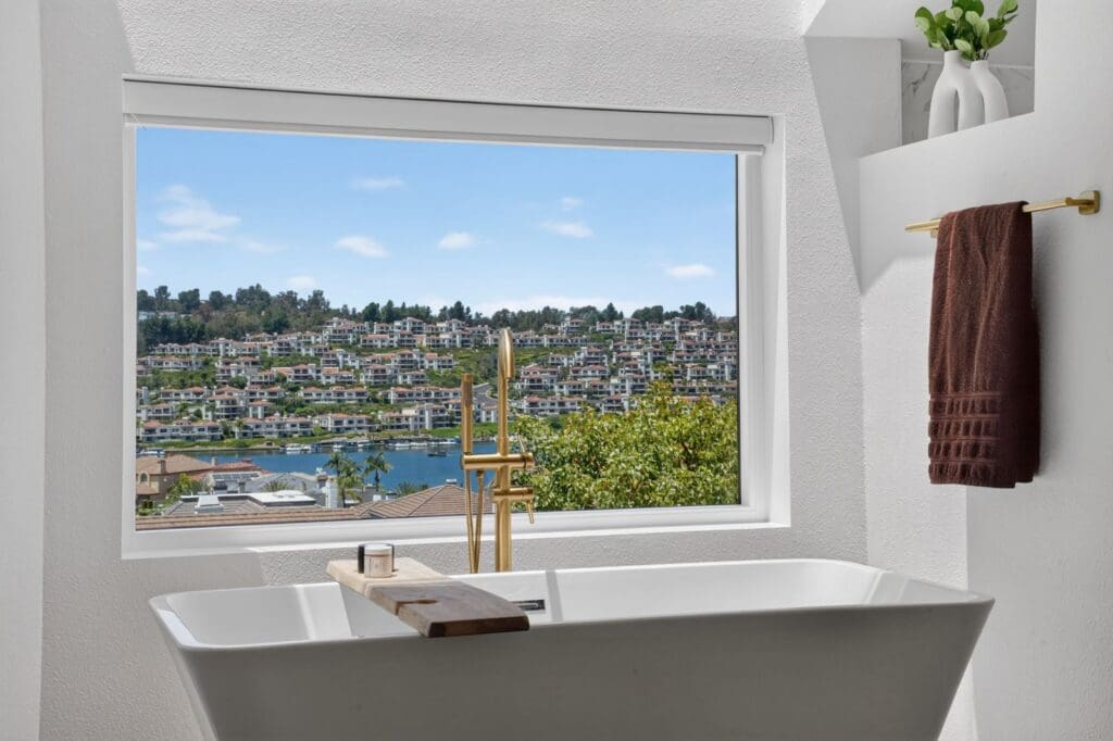 Primary bathroom with a freestanding soaking tub under a hillside view window in Mission Viejo