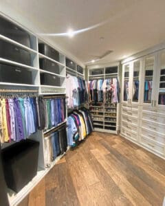 Primary closet hanging wall after unpacking, with shirts sorted by color and bins on the upper shelves, San Diego