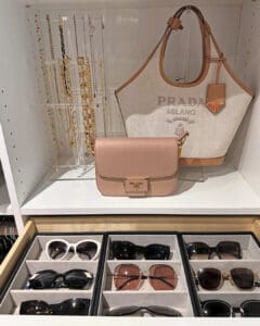 Primary closet shelf with a displayed handbag and necklaces above a velvet lined sunglasses drawer, San Diego