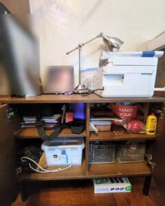 Printer shelf before organizing, crowded with cords, papers and loose supplies, San Diego
