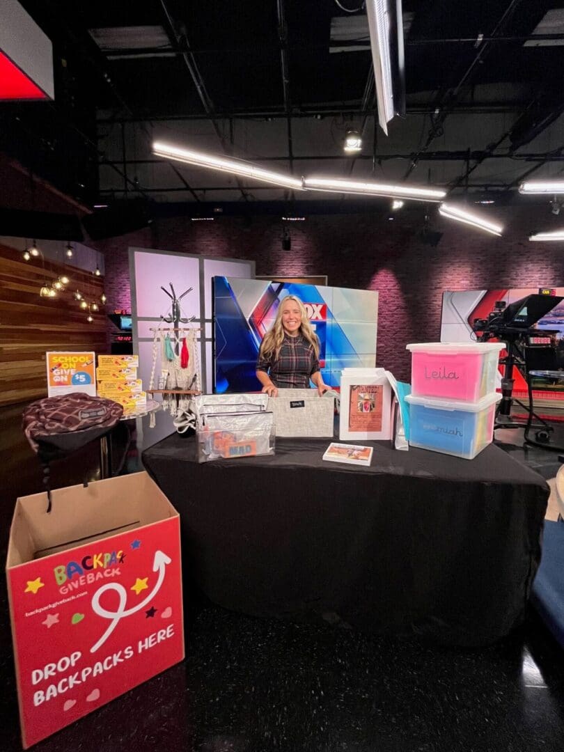 A person at a table with various colorful containers and boxes in a studio setting.
