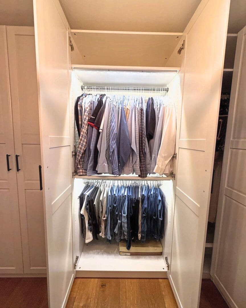 Lighted built-in closet with shirts and jeans hung by category after Simply Luxe move-in organizing in San Diego