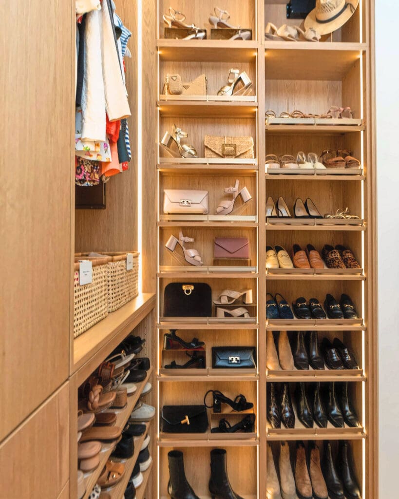 Same shoe wall after Simply Luxe organizing, with every pair and handbag displayed on lit shelves, San Diego