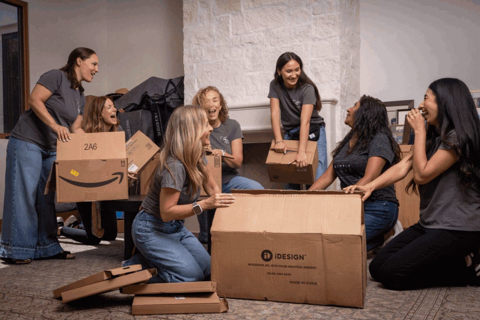 Group of women unpacking cardboard boxes indoors.